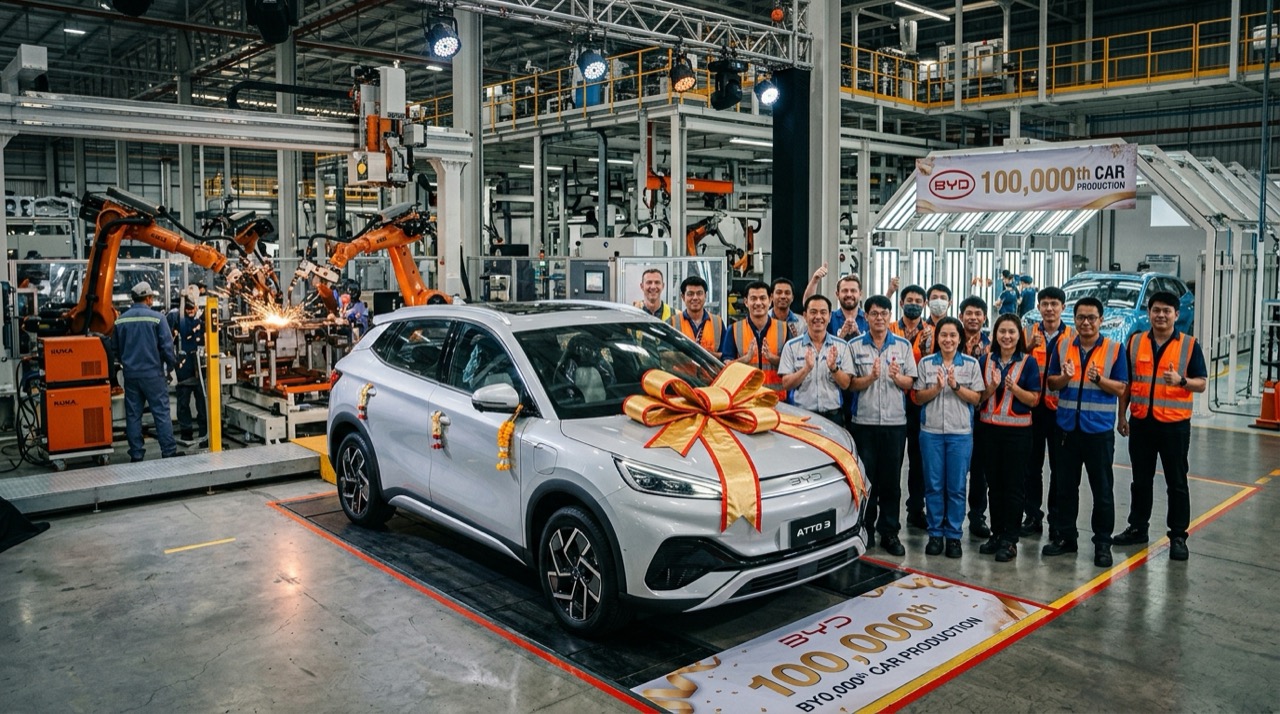 บรรยากาศพิธีเฉลิมฉลองการผลิตรถยนต์คันที่ 100,000 ณ โรงงาน BYD นิคมอุตสาหกรรม WHA ระยอง รถยนต์ไฟฟ้าสีบรอนซ์เงินผูกริบบิ้นทองท่ามกลางทีมวิศวกรและหุ่นยนต์แขนกลอุตสาหกรรม